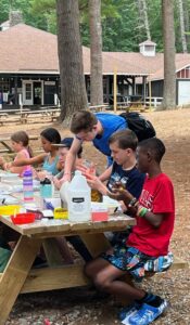 Campers sit at a picnic table to do arts and crafts at the YMCA Camp of Maine